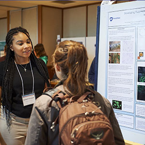 Students discuss a research poster