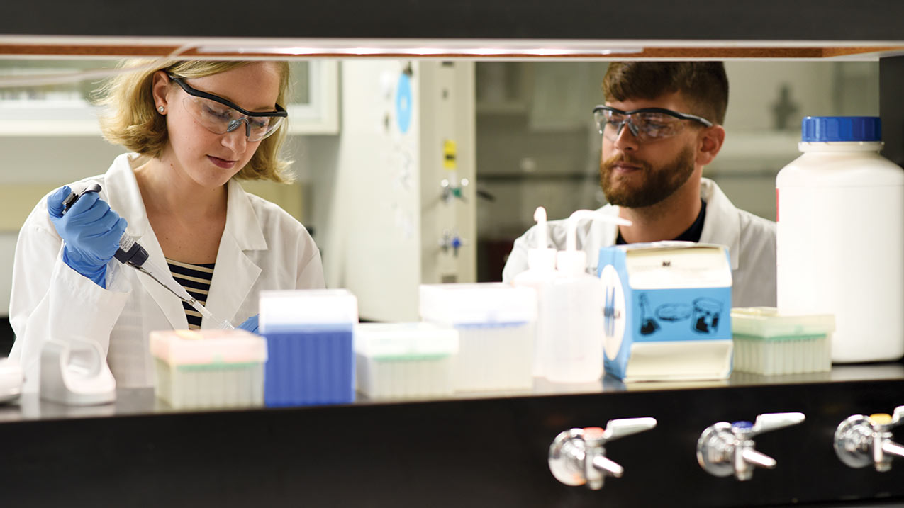 Student working in a lab with a lab tech.