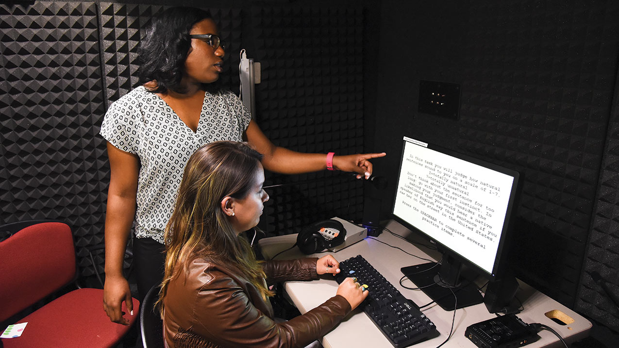 Students working in a computer in a sound proof booth.