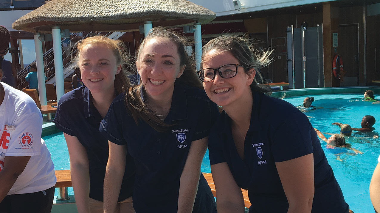 Students working at a booth on a cruise ship