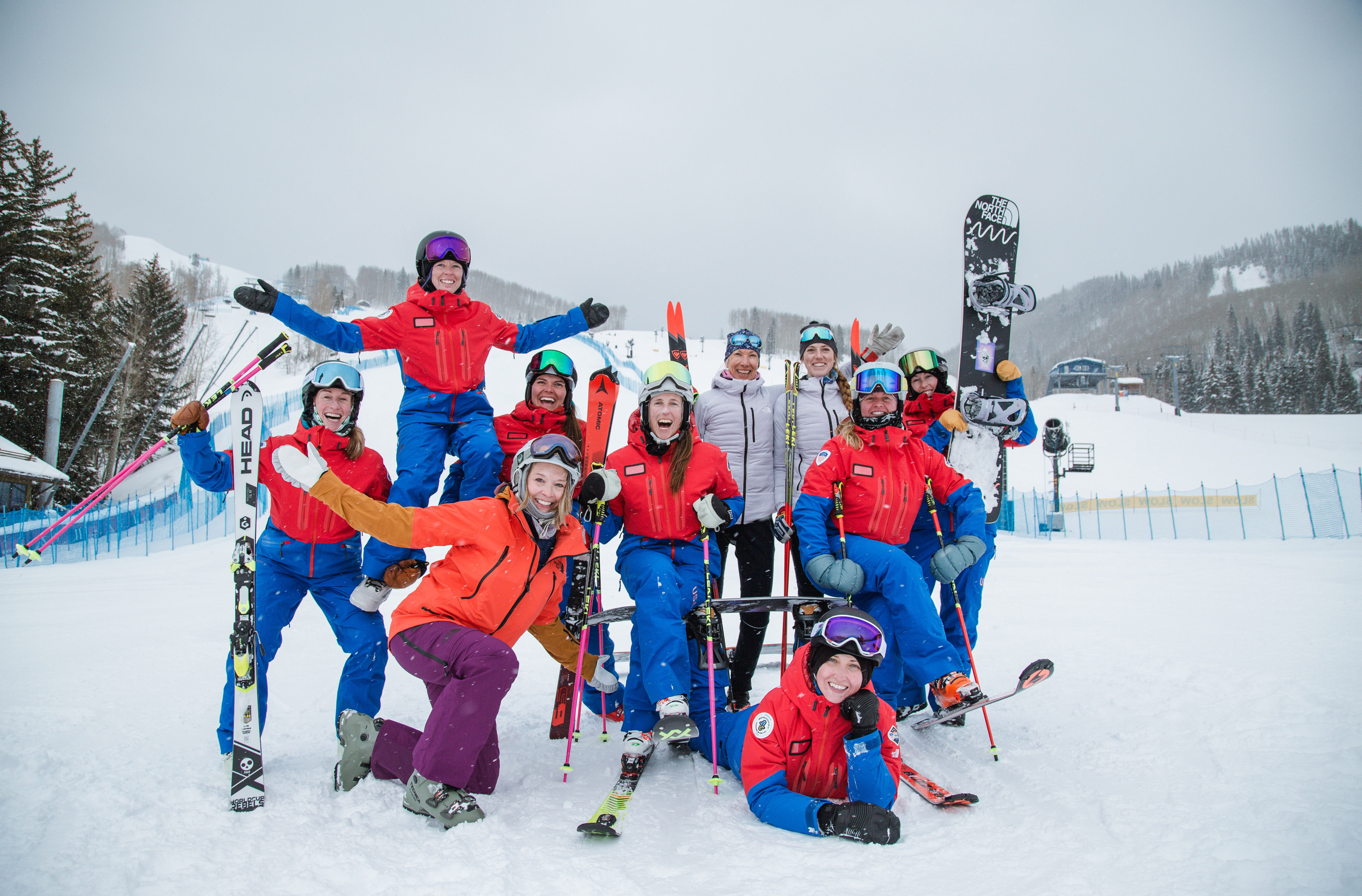 A smiling group of skiers and snowboarders at the top of a mountain