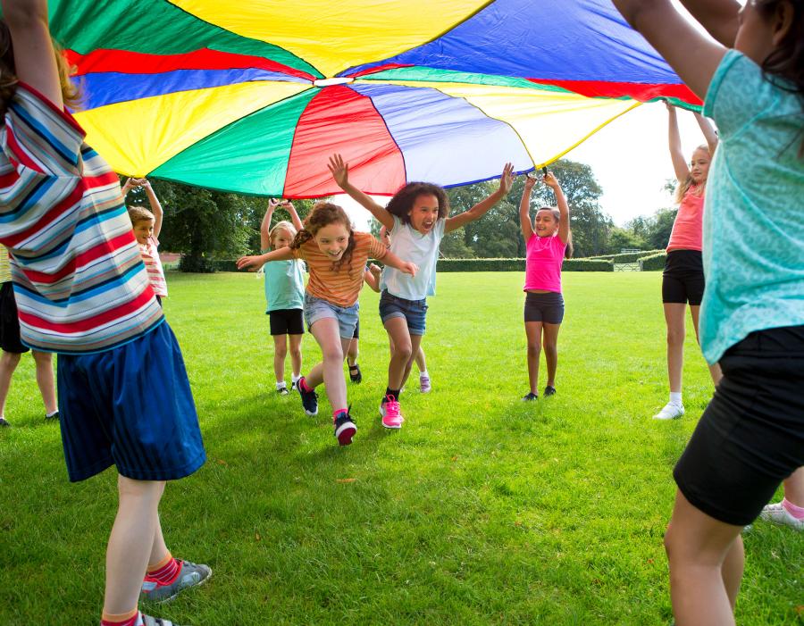 Children playing a game with a colourful Parachute