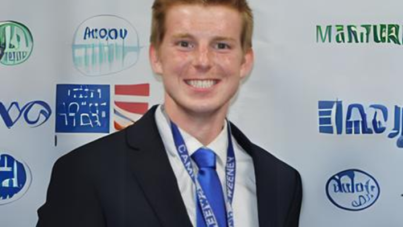 portrait of person with red hair wearing suit and blue tie