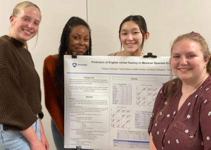 Four female students stand with their research poster.