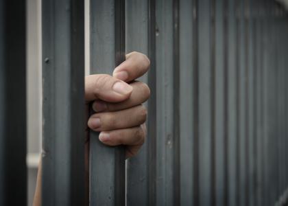 hand gripping jail bars