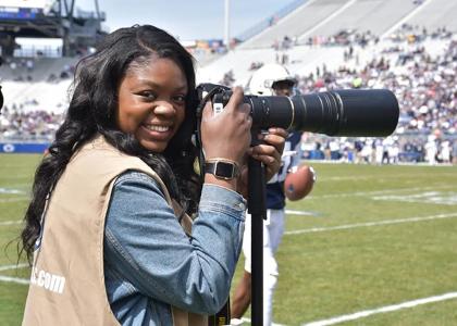 Adriana Lacy holding a camera while on the sideline at a football game