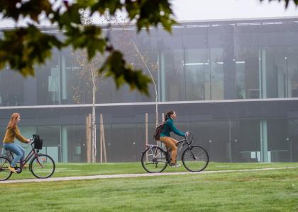 two women bicycling in front of a university building