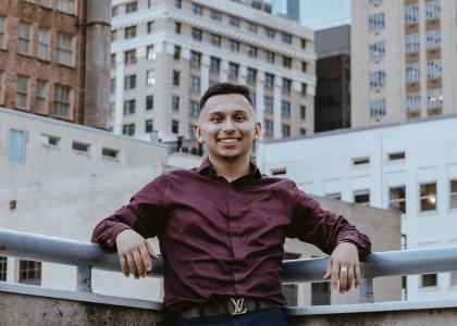 Liberal Arts student Michael Garza poses on a rooftop and smiles at the camera