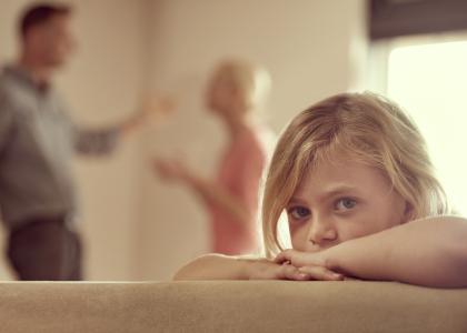 Image of a child with parents arguing in the background