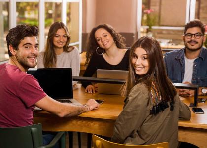 group of smiling college students sitting at table
