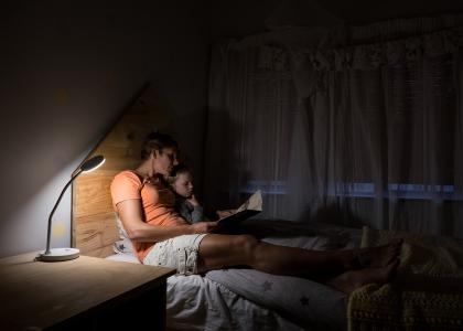 A mother reading to her daughter in bed at night.