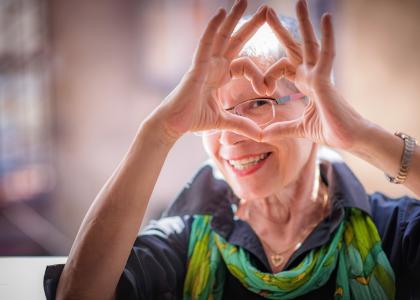 Older woman making a heart shape with her hands
