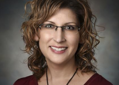 A woman in glasses smiles for her headshot