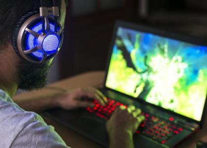Photo of a gamer wearing headphones and sitting at a desktop computer playing a game