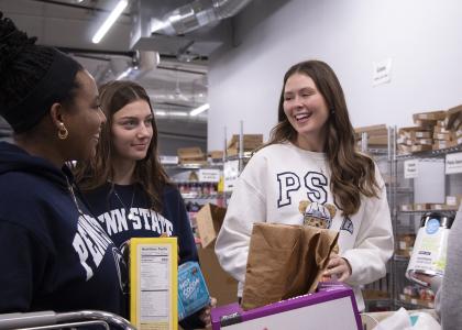 Four students standing around a bin of food donations helping sort them