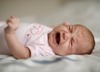 Newborn baby laying down and crying.