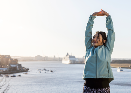 Woman in workout clothes stretching in front of harbor