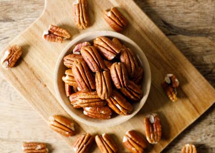 shelled pecans in a bowl on a cutting board