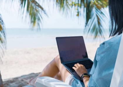Woman using laptop on the beach
