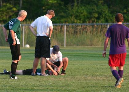 Soccer players looking at injured play laying on the ground