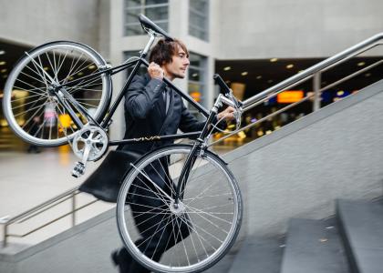 man in business suit carrying bike