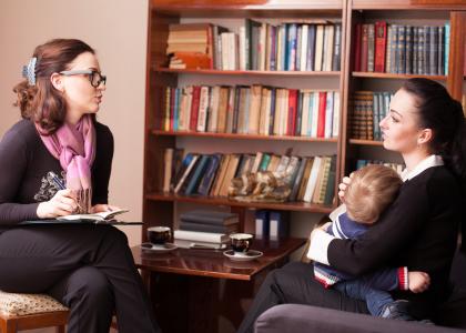 Woman talking to woman holding baby in office