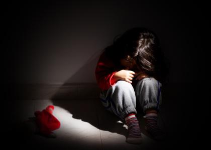 Dark, child huddled on floor