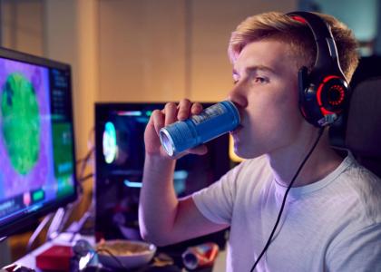 young male drinking soda while playing video games