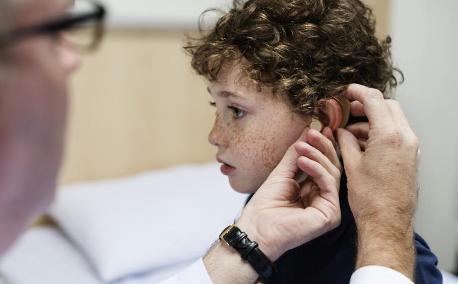 A doctor is fitting a hearing aid in a young child. 