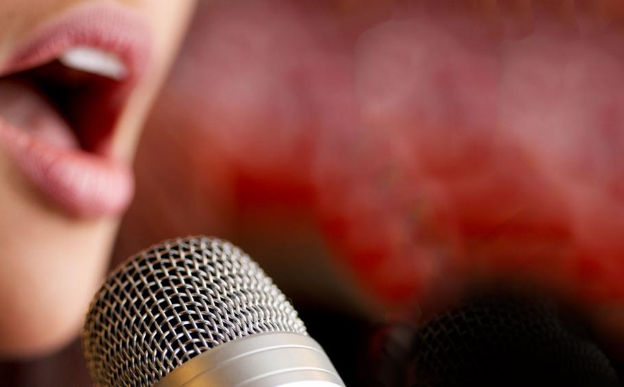 Close up of a woman singing into a microphone. Red and black background