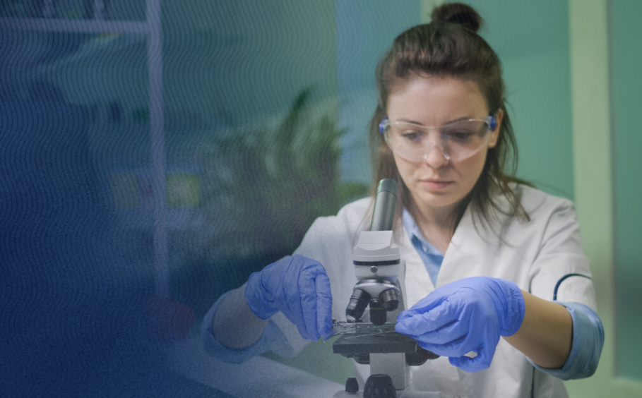 A woman adds a slide to a microscope in a lab. 