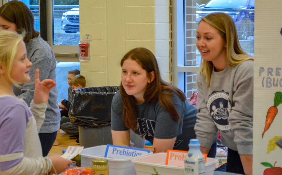 Students speaking with children at nutrition fair. 