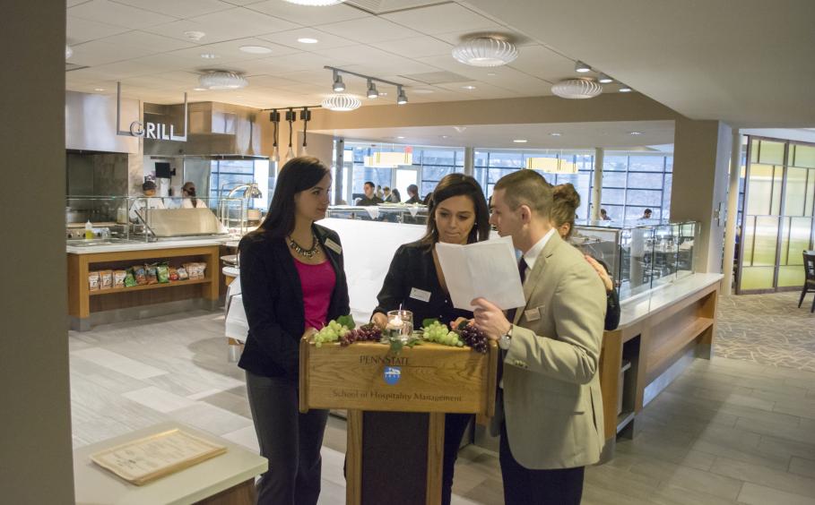 Three students standing at the host stand in Cafe Laura.