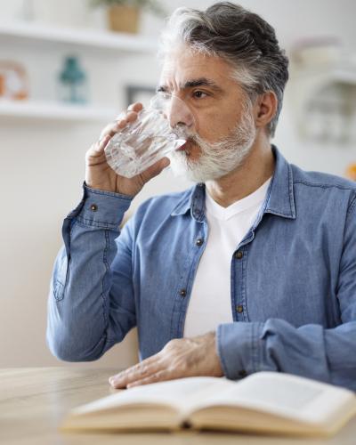 Older man drinking water sitting at a table