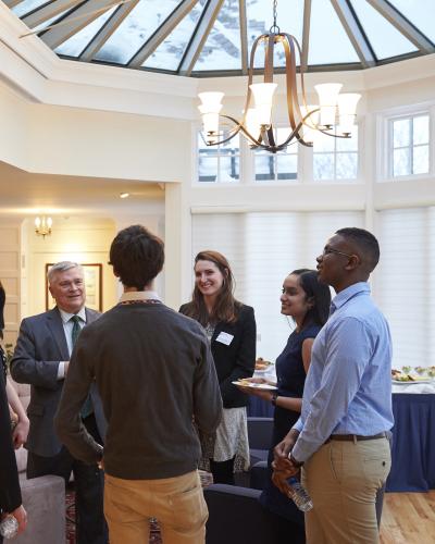 President Barron talking with several students in a group at a reception. 