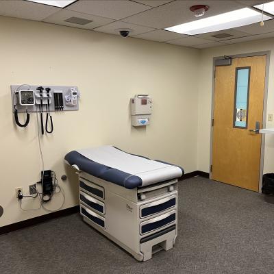 The primary care room contains an examination table and healthcare equipment mounted on the wall.