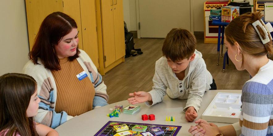 Speech-Language Pathology students play a game with two children