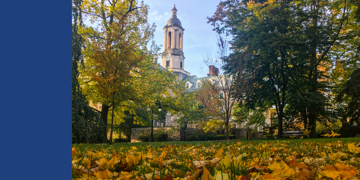 Old Main through autumn trees and leaves on lawn. 