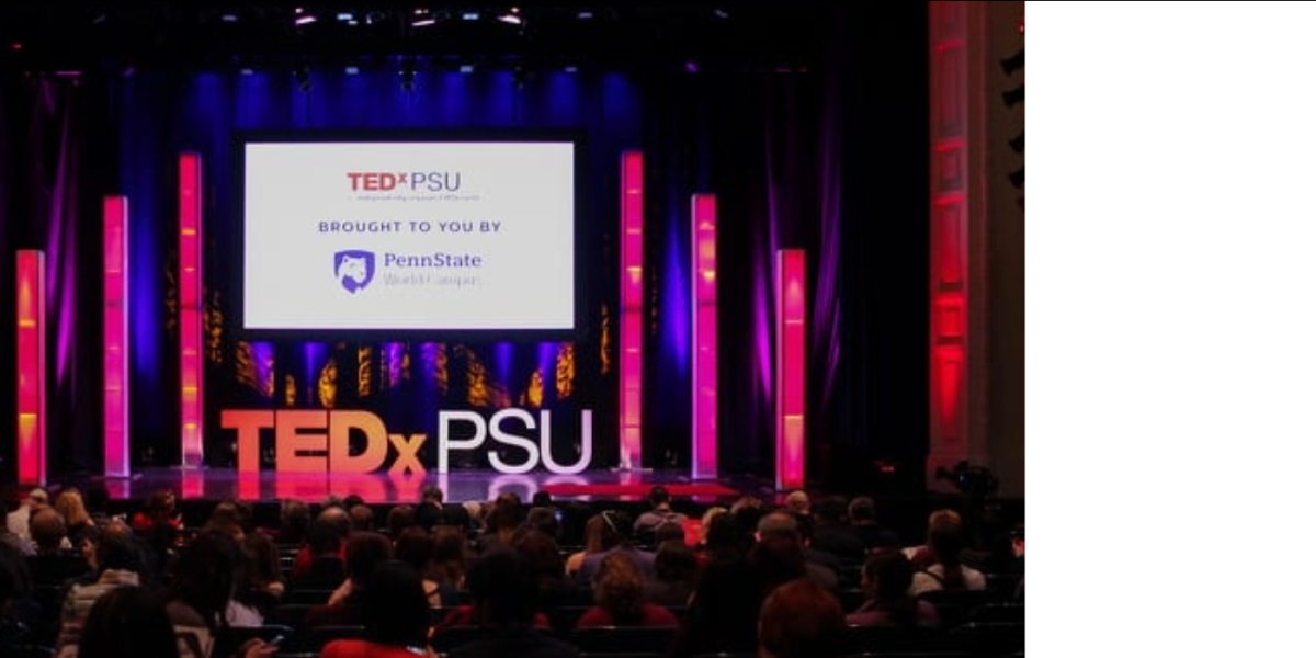 Attendees of TEDxPSU seated in the auditorium in front of the conference setup.