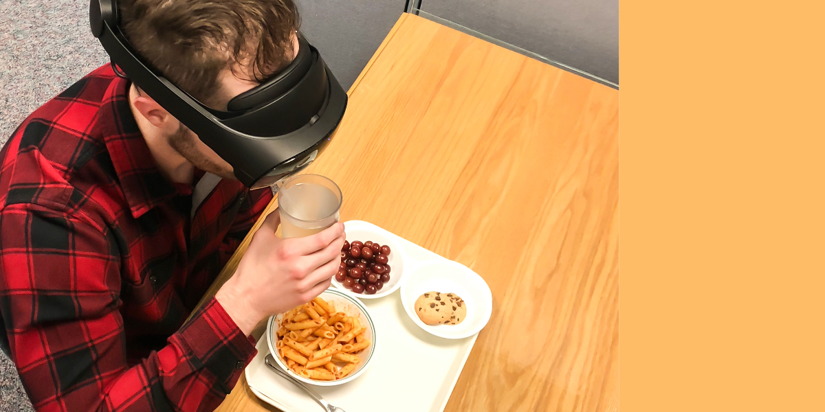 Man wearing virtual reality headset while sitting to eat a meal. 