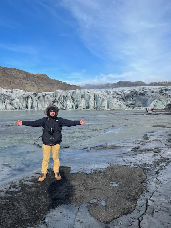 Mathias standing on a glacier with his arms open